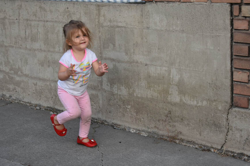 Photo of a little girl in front of a cement wall
